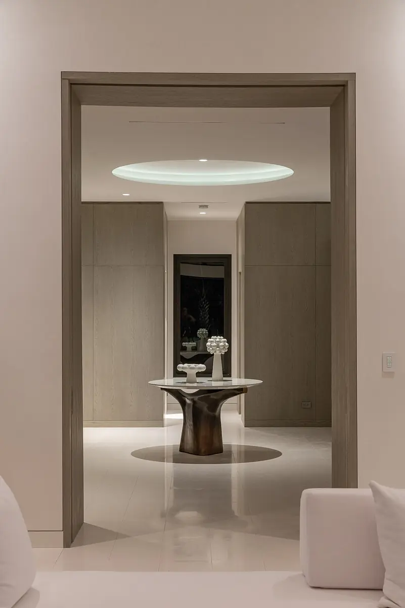 Foyer with round table, light-colored panel walls, and circular recessed light fixture.