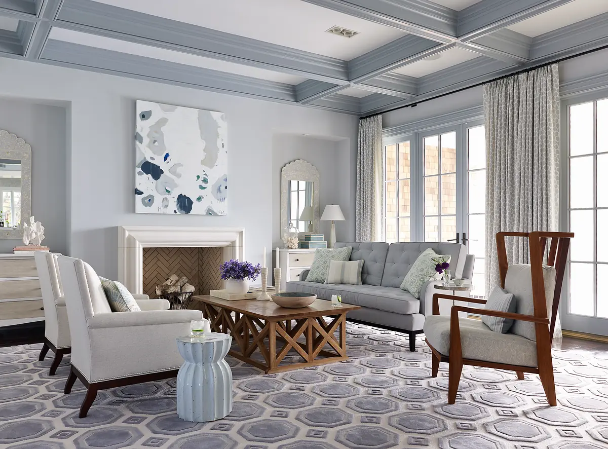 Living room with gray sofa, wooden coffee table, armchairs, area rug, fireplace, and large windows with curtains