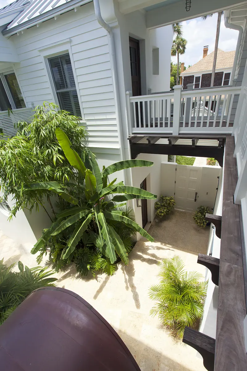 Exterior area with balcony, palm trees, tropical plants, stone flooring, and white door