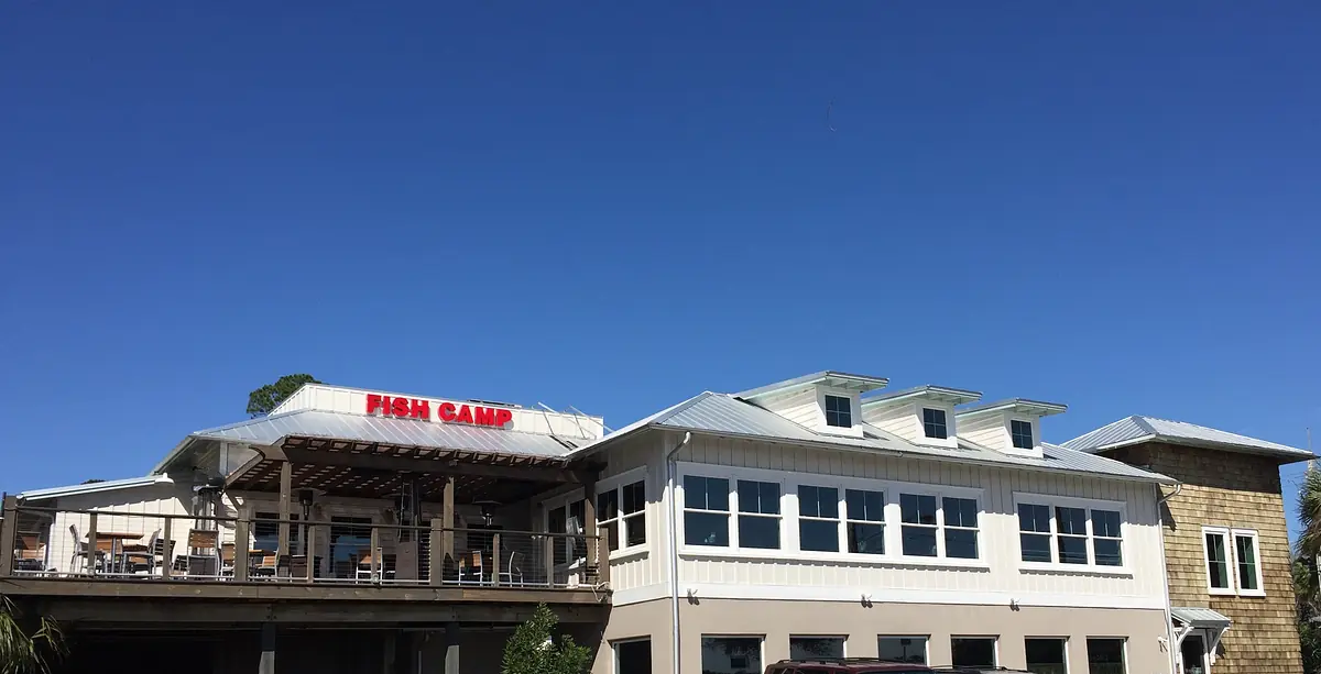 Exterior of a restaurant named 'FISH CAMP' with deck area, multiple windows, and pitched roofs