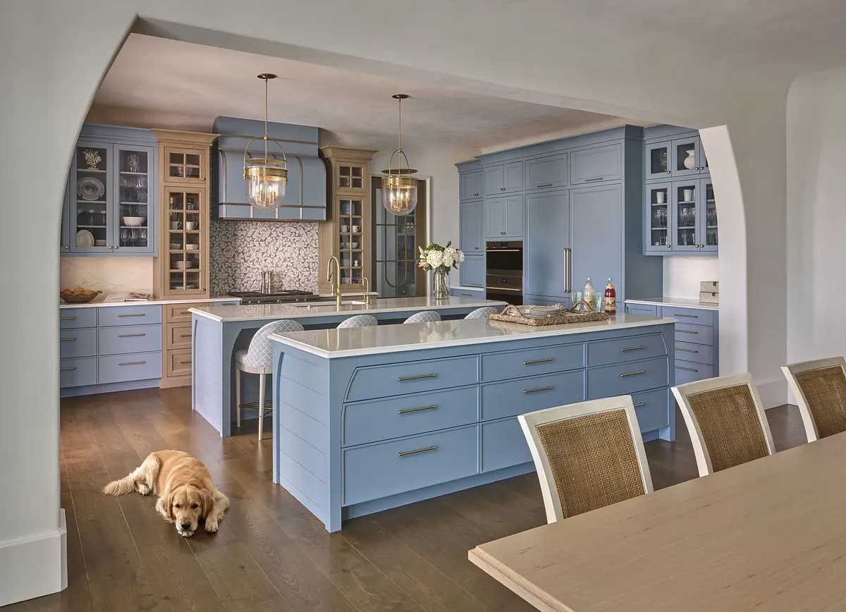 Kitchen with blue cabinetry, white countertop, large island, glass cabinets, and dining area