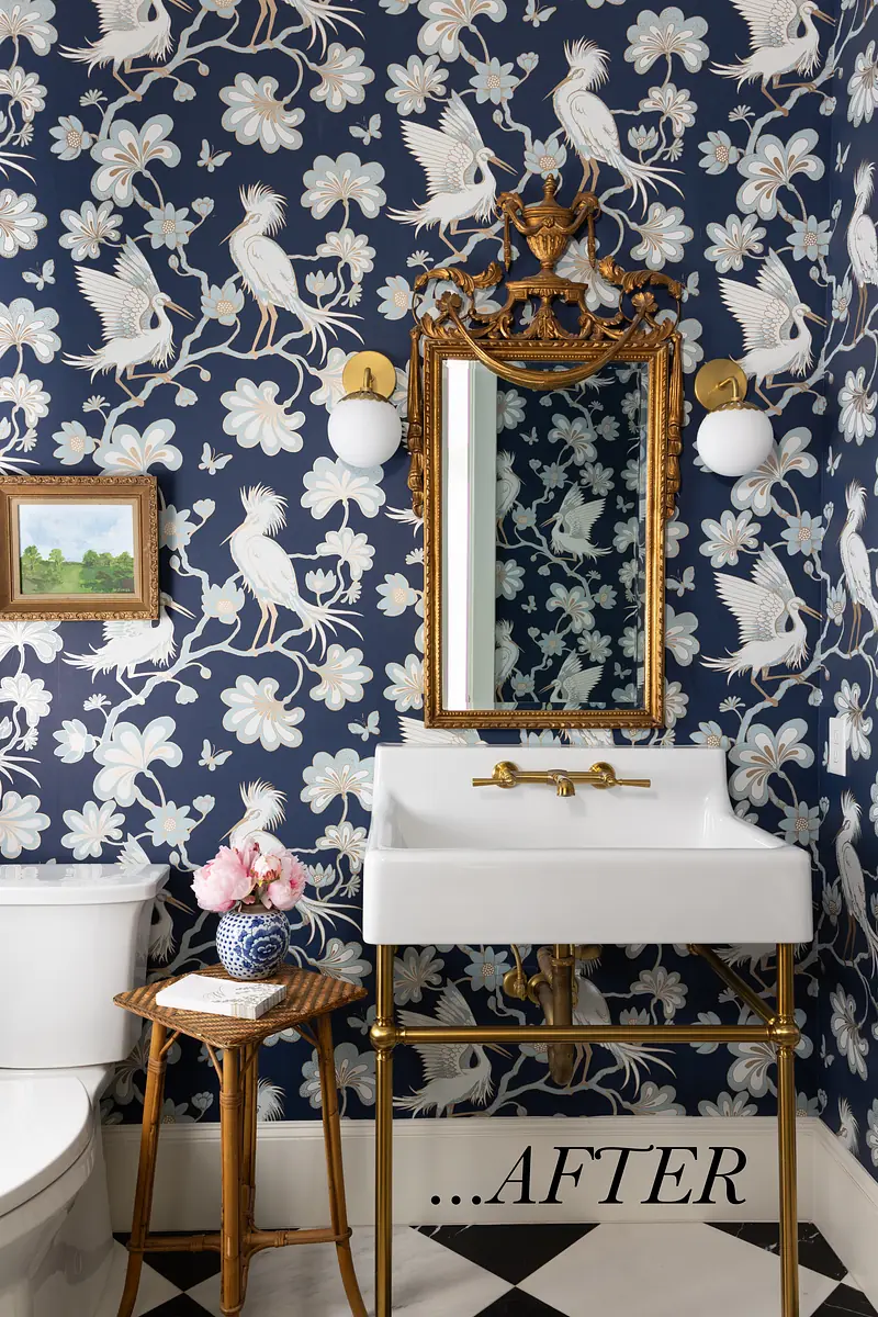 Bathroom with white pedestal sink, gold fixtures, dark floral wallpaper, and checkered black and white tile floor.