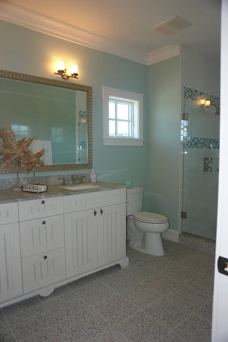 Bathroom with white vanity, light gray countertop, glass shower, and light blue walls.