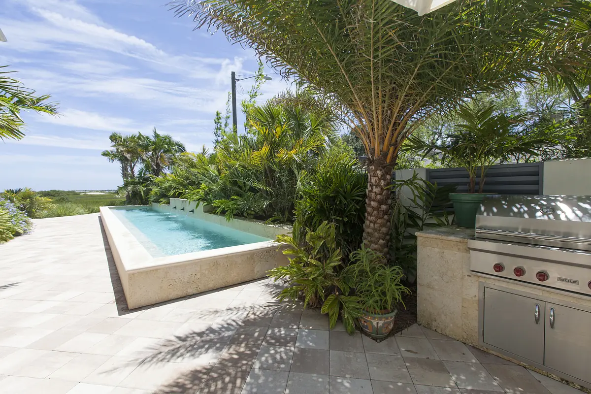 Patio with swimming pool, tropical plants, built-in grill, and light-colored tiled flooring