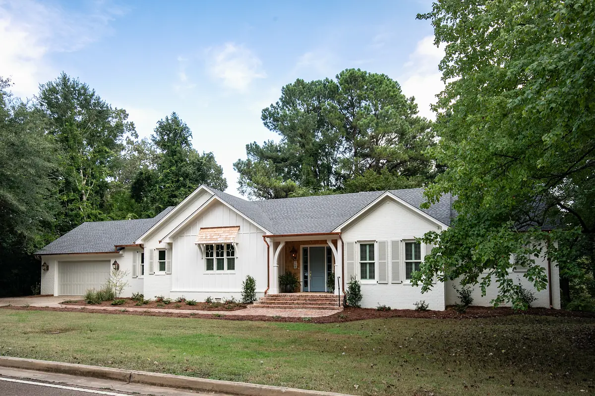 Front exterior of a single-story house with gabled roof, brick accents, and landscaped yard.