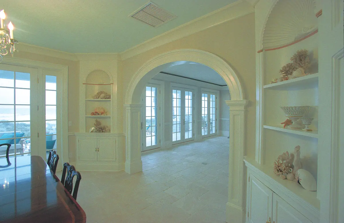Dining room with dark wood table, black chairs, built-in shelves, large windows, and seashell decor.